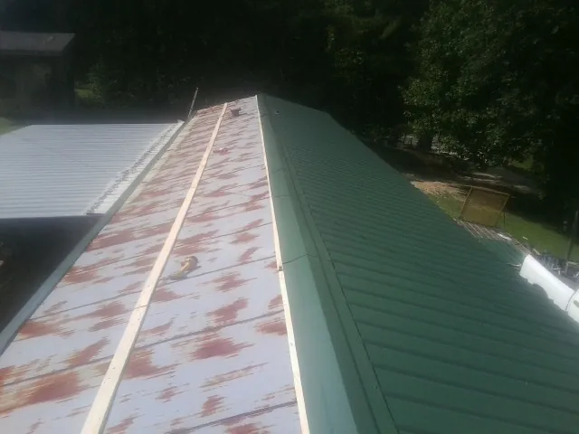 Old rusted panels beside newly installed green metal roofing — Wind Damage Roof Repair by Roofing Brothers in Jordan
