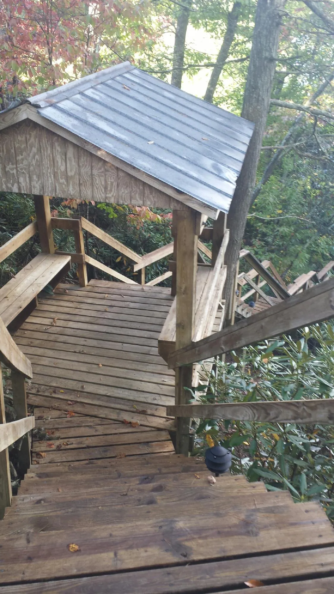 Metal roofed shelter over wooden steps on a wooded walkway — Skylight Repair & Installation work by our crew in Jordan
