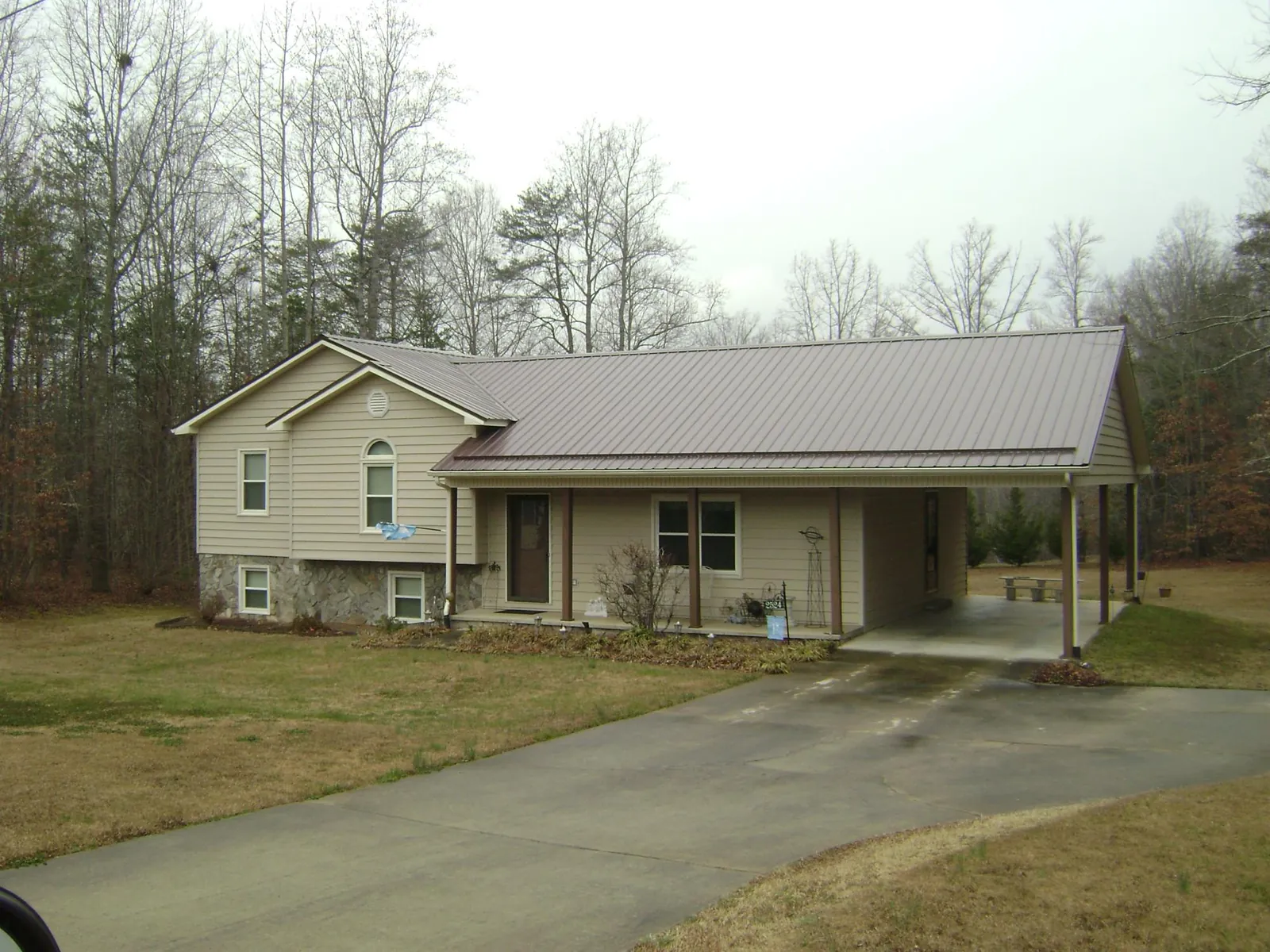 Brown metal roof on a tan split level home with an attached carport in Jordan