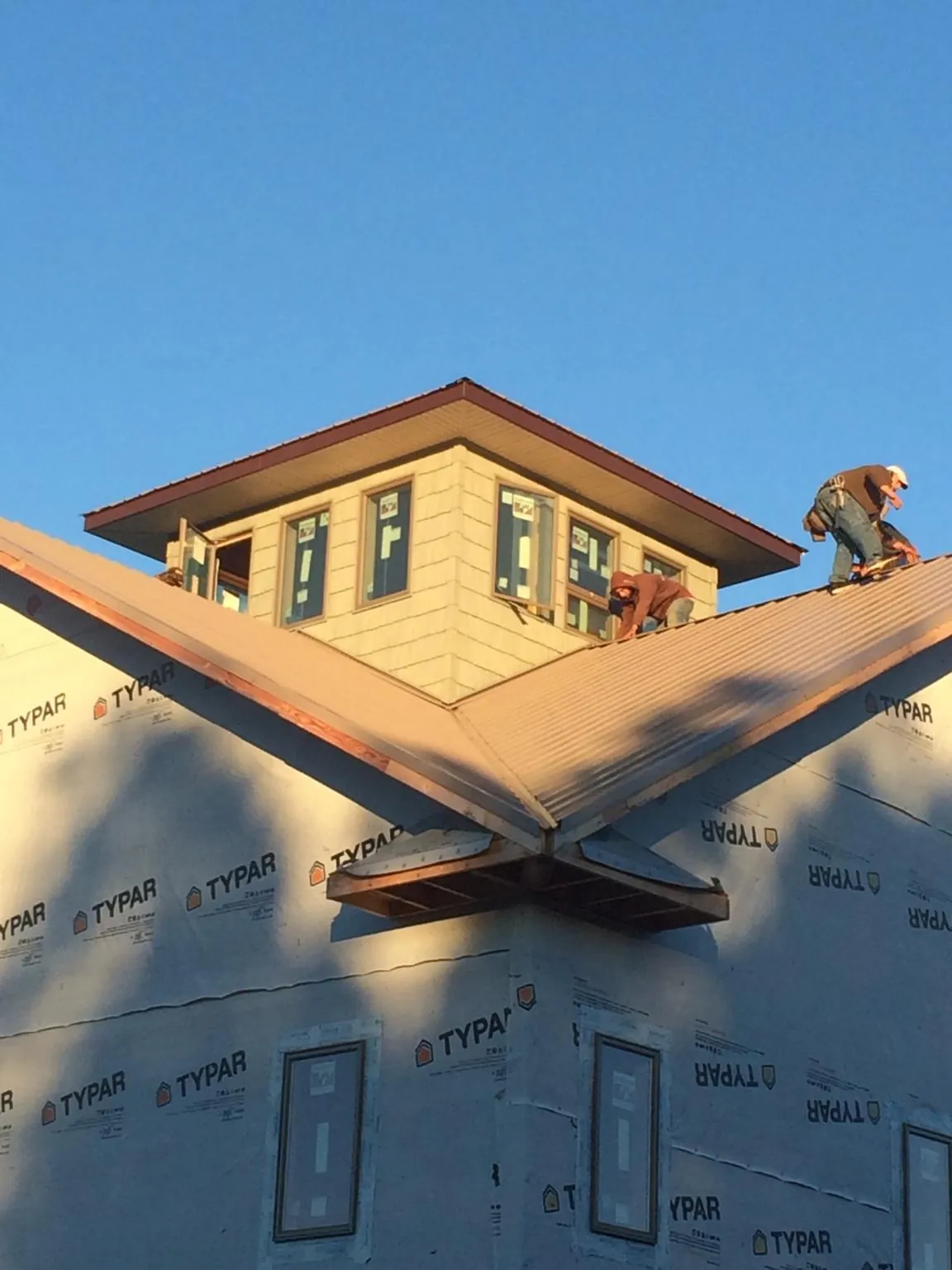 Roofers working around a rooftop cupola on a new metal roof at sunset — Roof Waterproofing in Jordan by Roofing Brothers